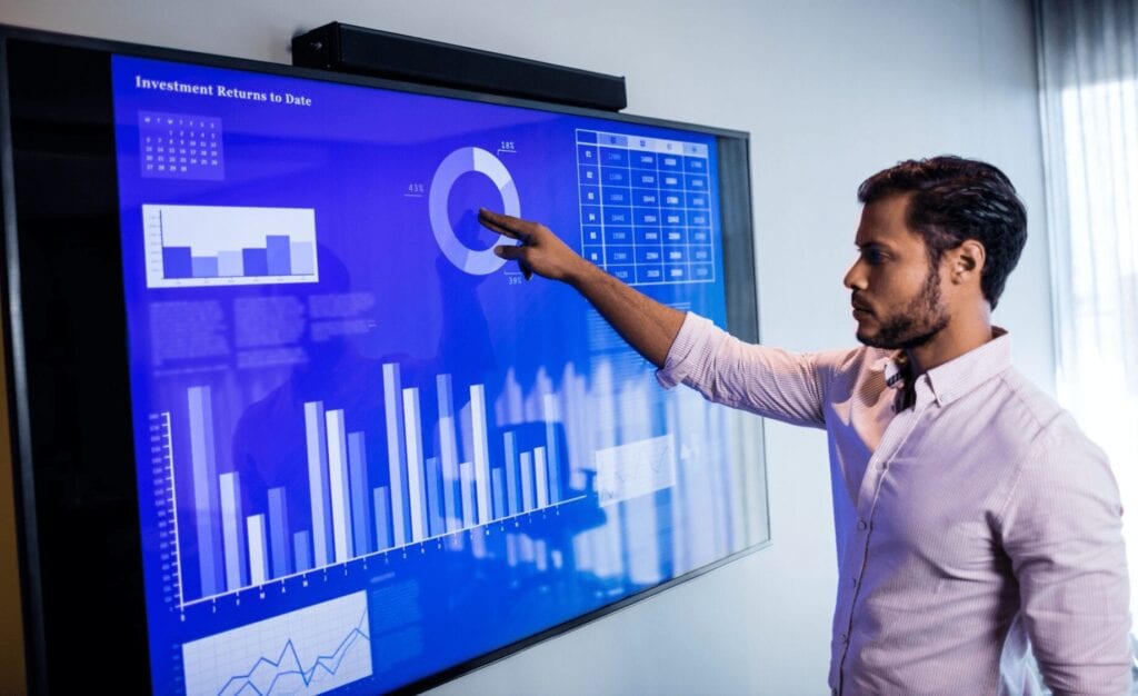 Man investigating graphs on a large screen